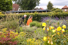 Bewohner und Mitarbeiterin flanieren im Garten der Wohngruppe